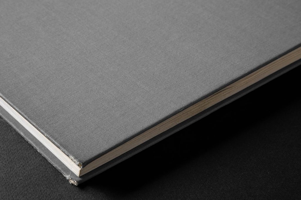 Buku hardcover dengan lembaran halaman putih dan cover hitam