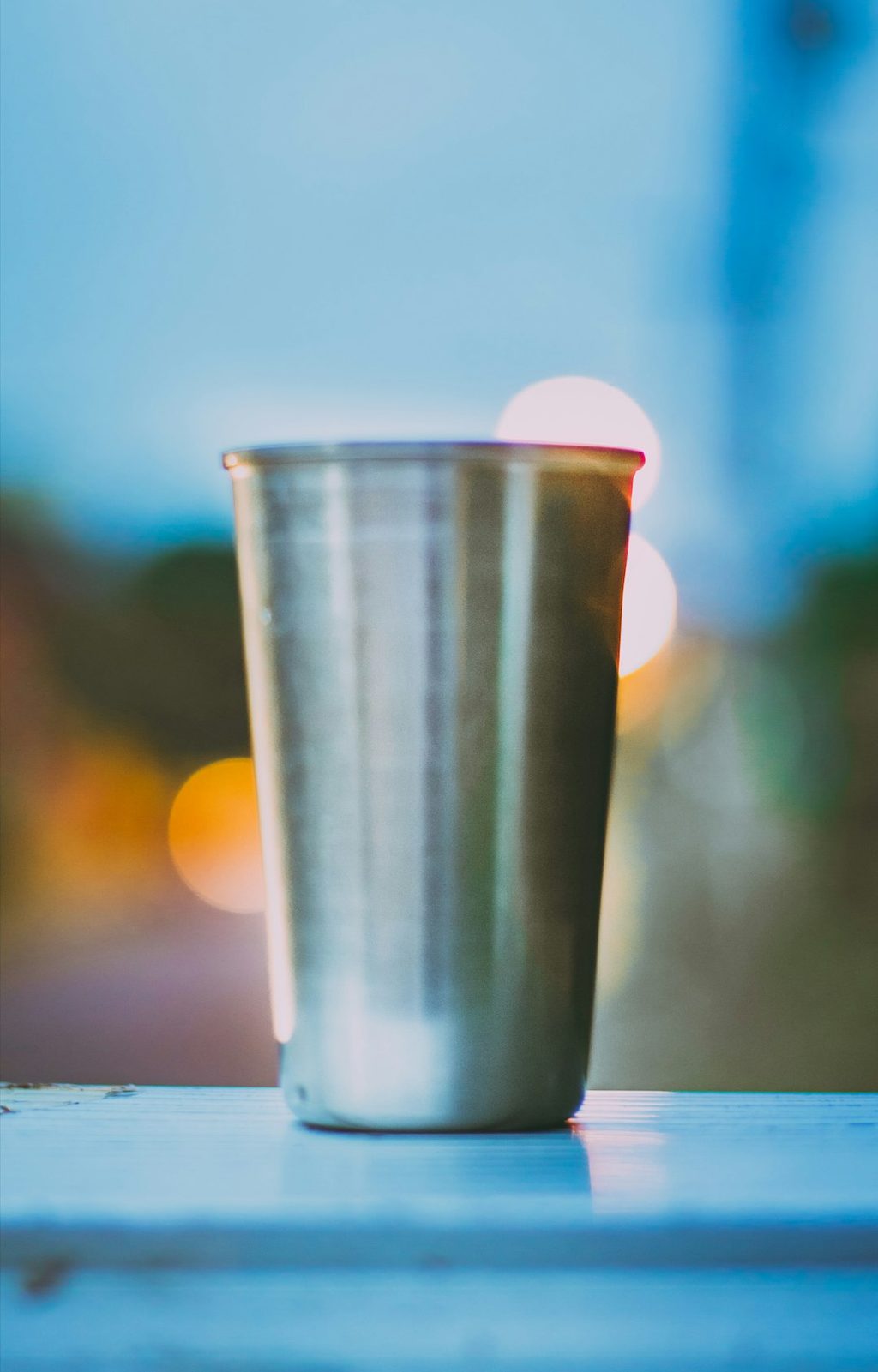 Gelas stainless modern dengan cahaya bokeh di latar belakang.