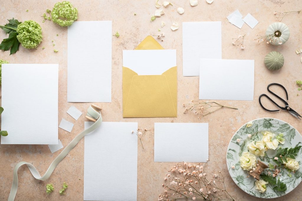 Rangkaian paket percetakan online dengan kertas putih, kuisioner, dan aksesori dekoratif.